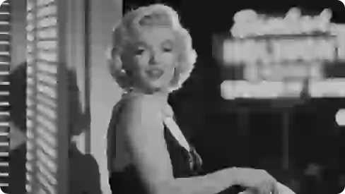 Bức ảnh đen trắng chụp Marilyn Monroe mặc váy đen và đeo vòng cổ ngọc trai.
