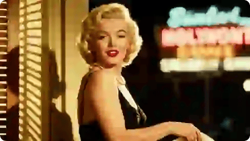 Bức ảnh màu chụp Marilyn Monroe mặc váy đen và đeo vòng cổ ngọc trai.