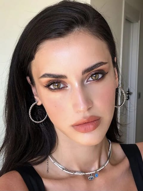 Selfie d'une femme aux cheveux noirs raides, boucles d'oreilles et collier en argent, posant dans une scène intérieure. Modèle pour l'échange de visage d'image.