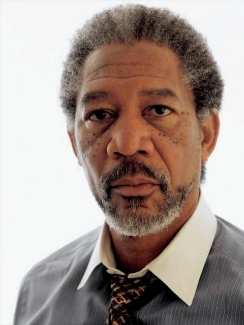 Portrait de Morgan Freeman aux cheveux courts gris poivre et sel à texture afro. Il porte une chemise à fines rayures gris clair avec un col blanc impeccable et une cravate foncée à motifs, sur un fond blanc uni avec un regard calme et direct vers la caméra. Modèle pour l'échange de visage d'image.
