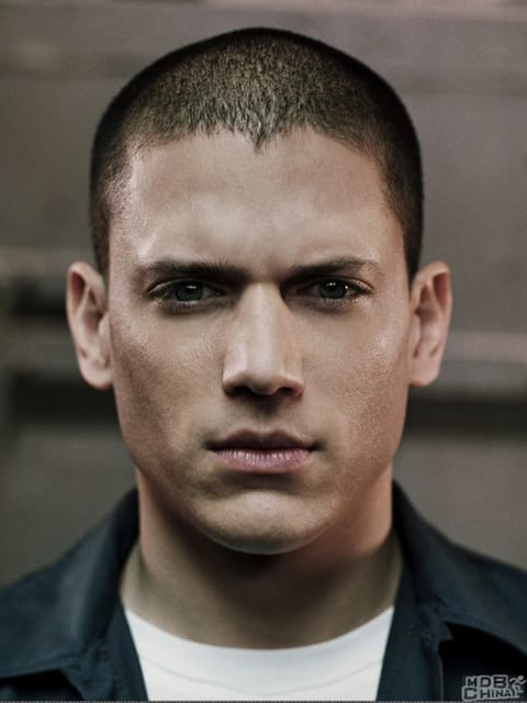 Gros plan de Wentworth Miller avec une coupe buzz et une expression sérieuse et intense. Il porte un blazer noir associé à un haut blanc. Modèle pour l'échange de visage d'image.