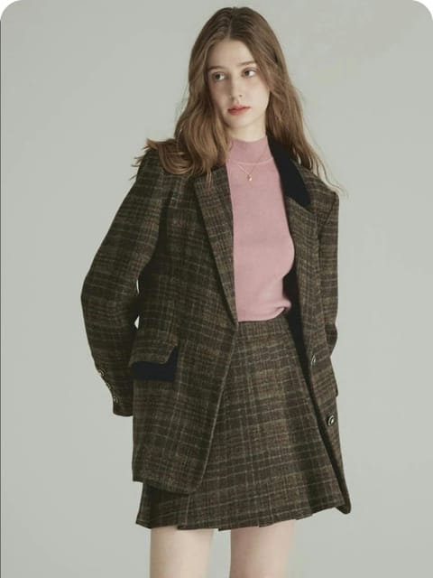 En kvinne i rutete blazer og skjørt sett med en rosa topp, sammen med brune sko og hvite sokker, modell for AI-klærbytte.